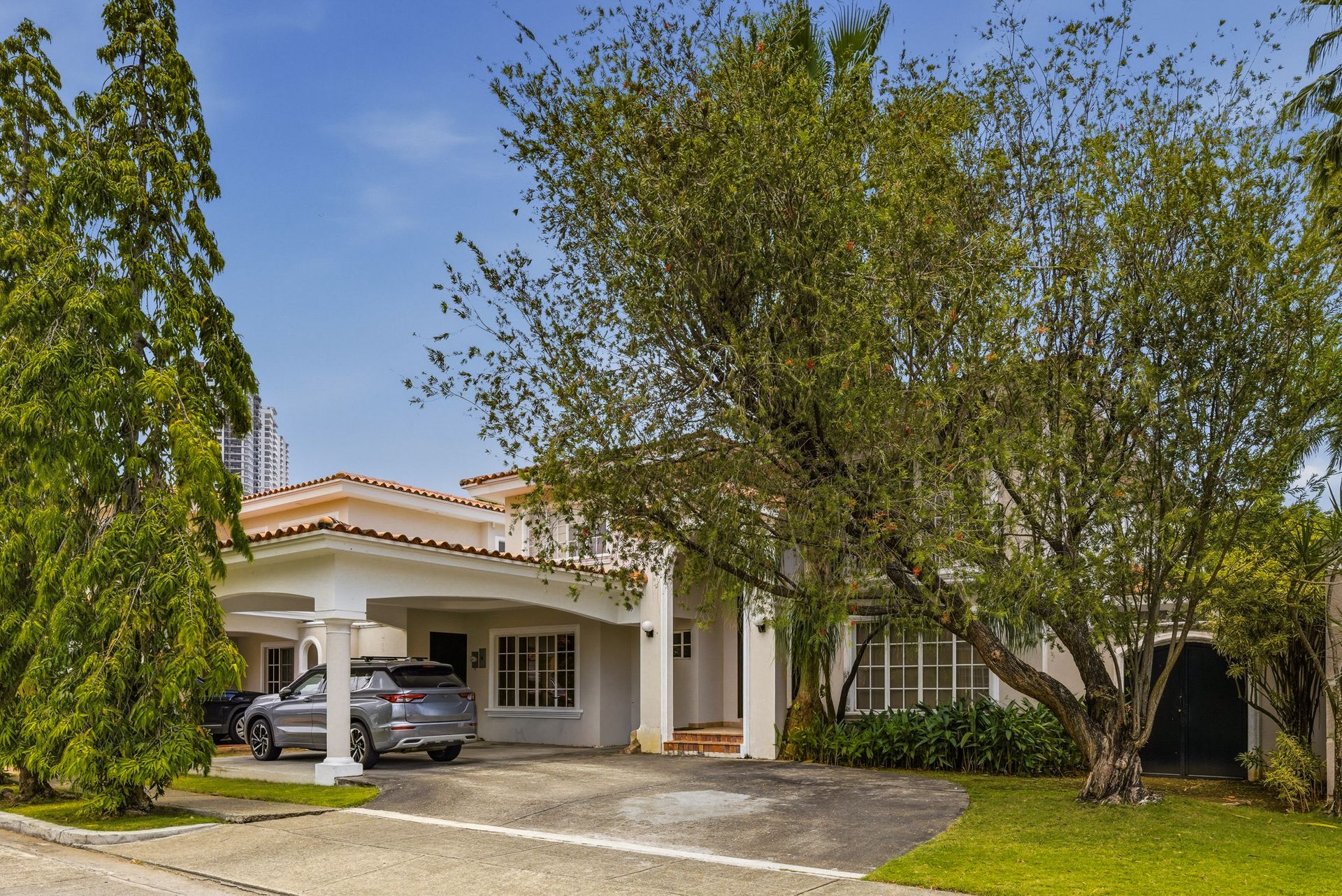 Costa del Este luxury home facade framed by mature trees and tropical landscaping, Panama real estate photography.