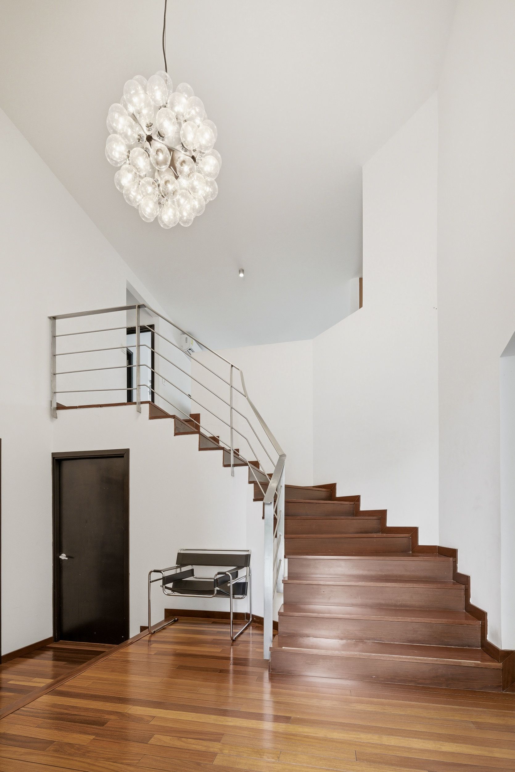 Costa del Este double-height entry with wooden staircase and sputnik chandelier, Panama luxury real estate.