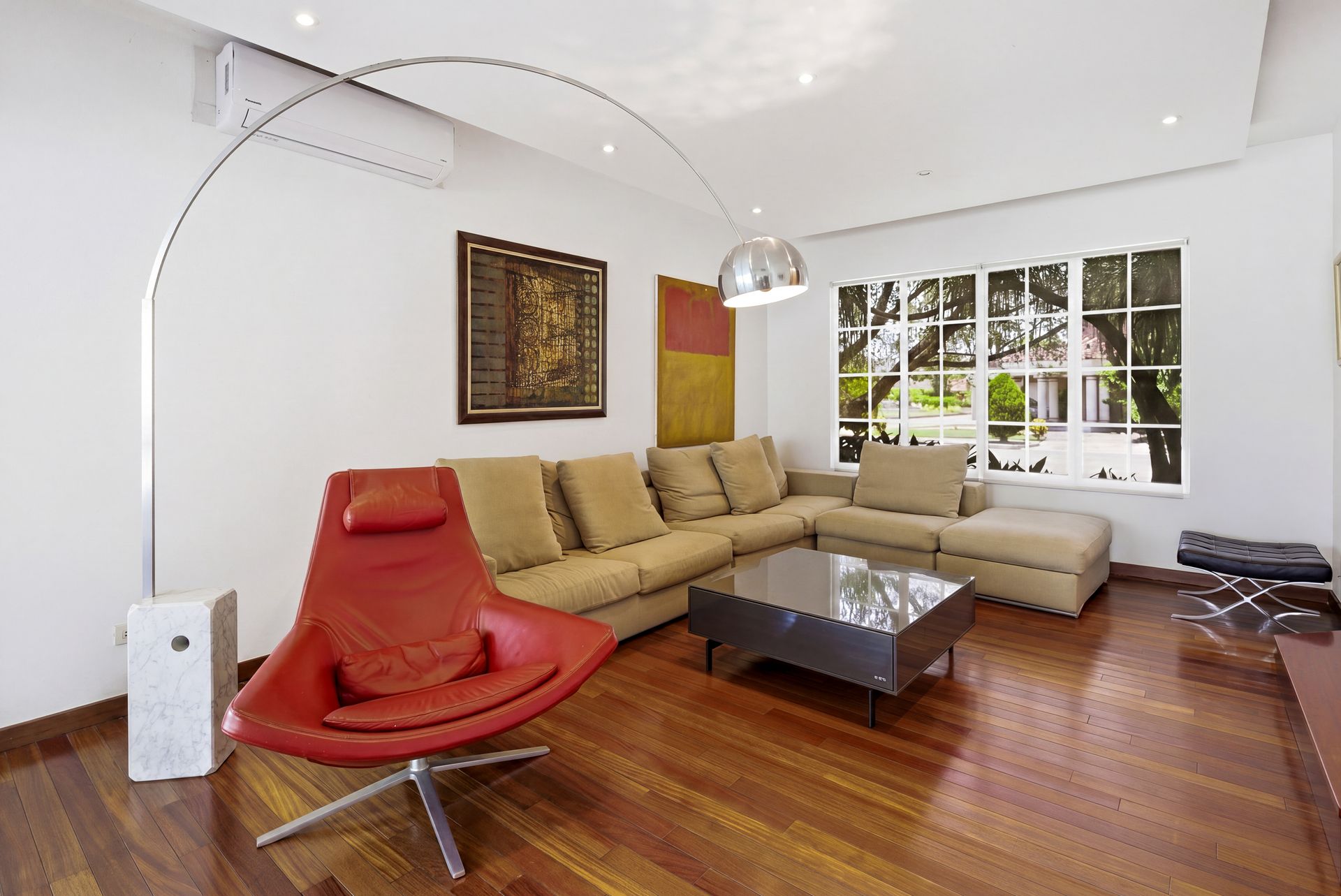 Costa del Este luxury home living area with designer red accent chair and sectional sofa, Panama real estate photograph