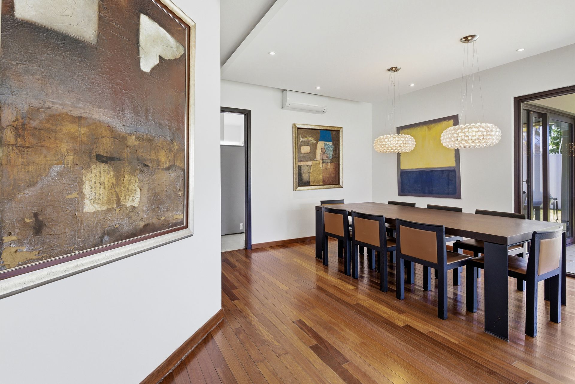 Costa del Este home formal dining room with long wooden table and contemporary art, Panama luxury real estate.