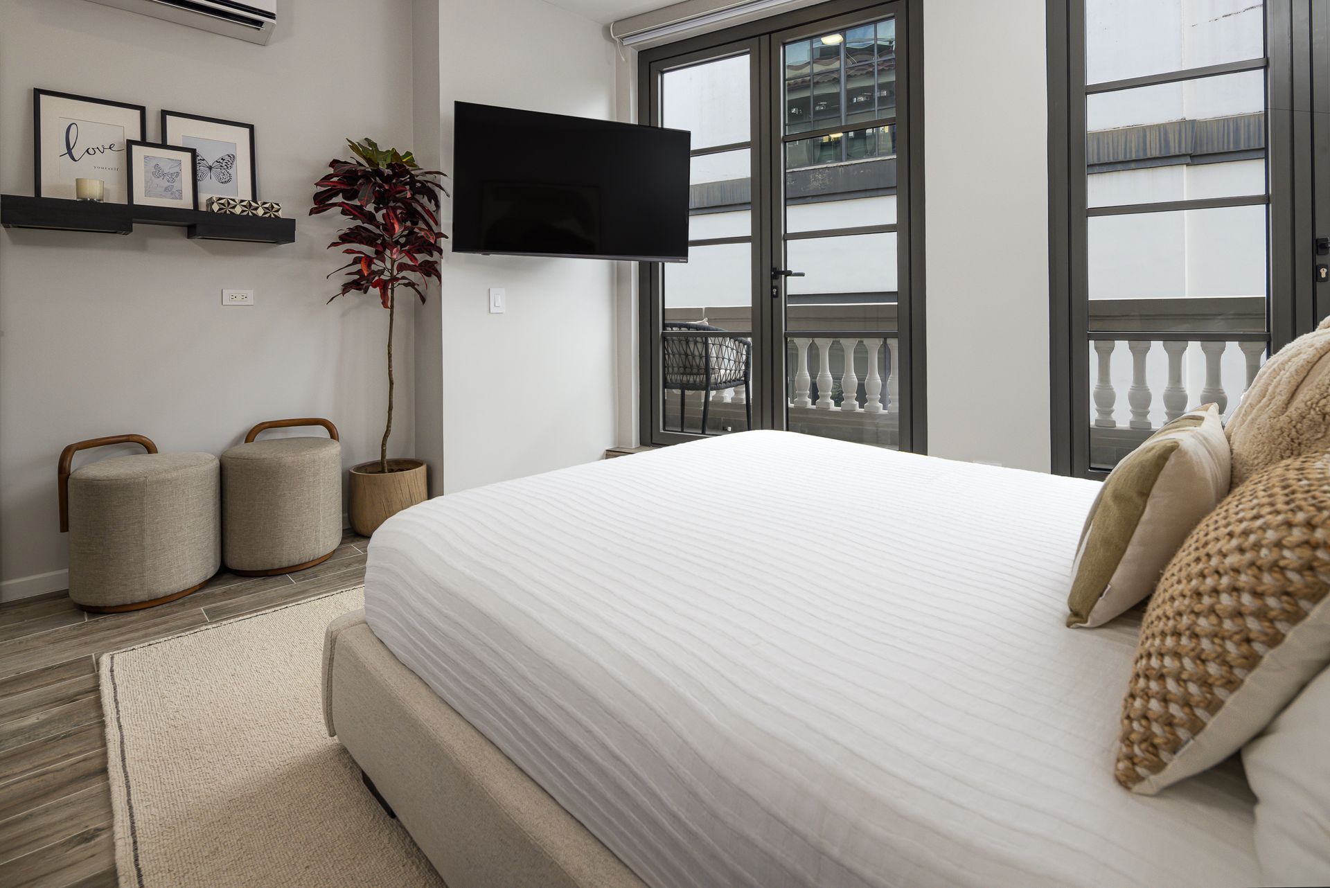 Bedroom with bed, TV, balcony, and decorative items. real estate photos by ivan marquez panama