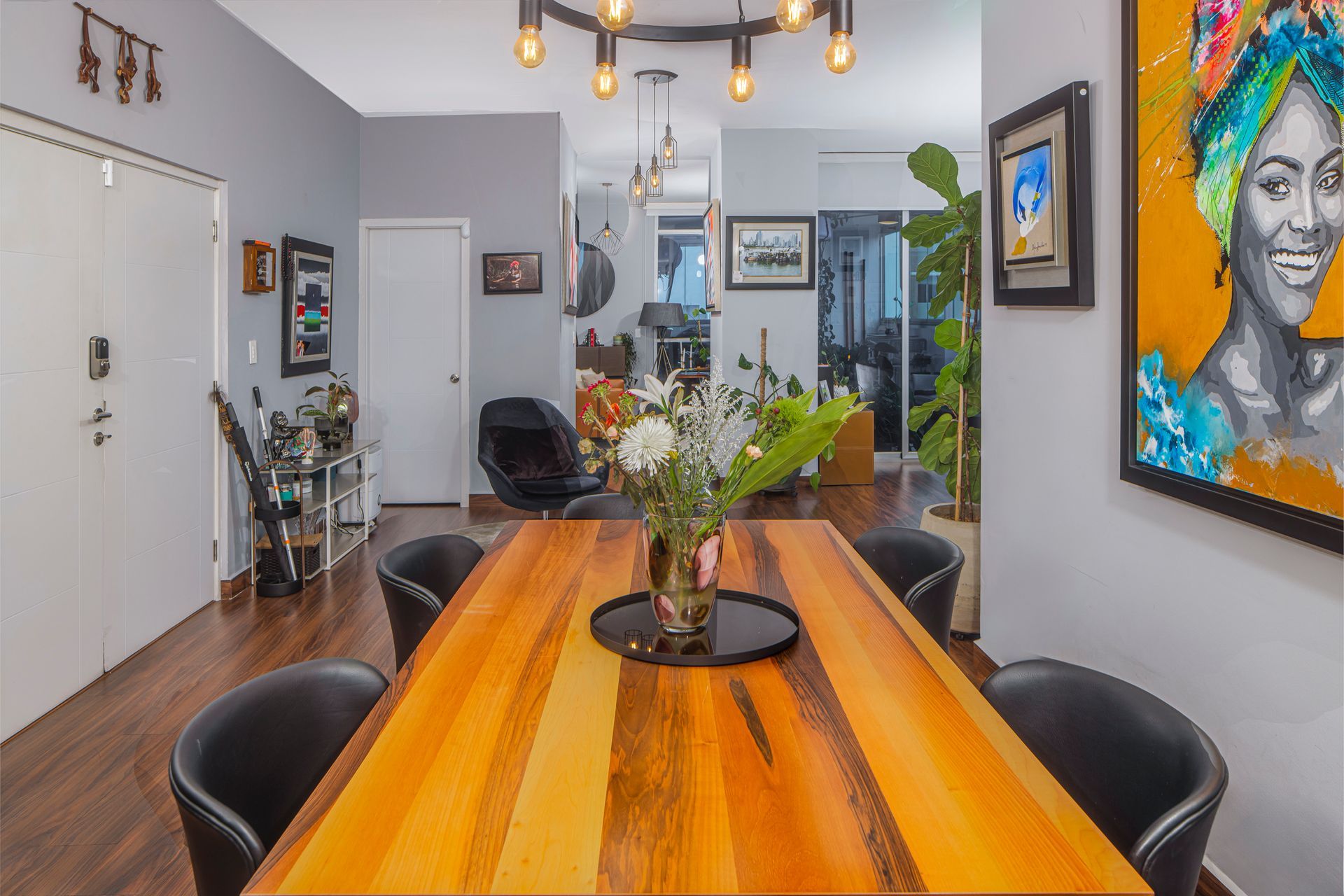 Dining room with wood table, black chairs, artwork, and modern chandelier.