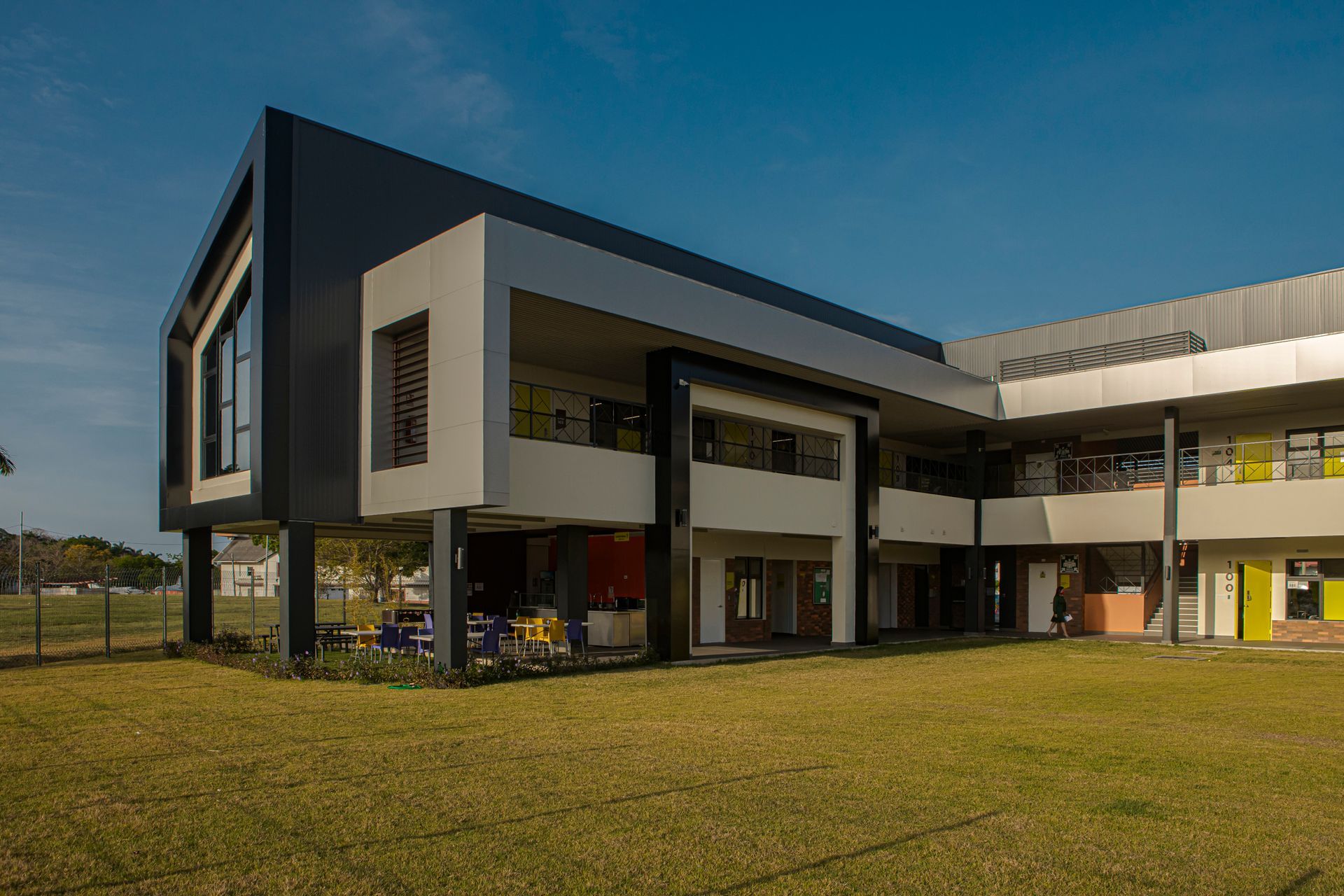 Modern two-story building with a black and white facade, sitting on grassy lawn under a clear blue sky.