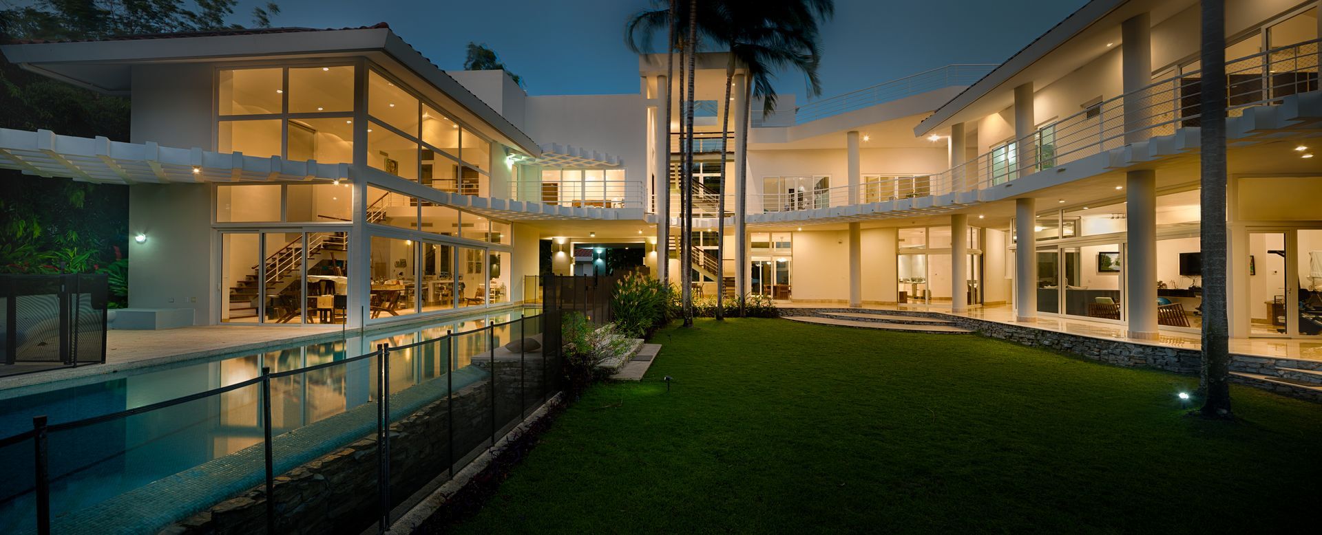 Modern luxury mansion exterior with glass walls and swimming pool at Punta Barco Resort, Panama.