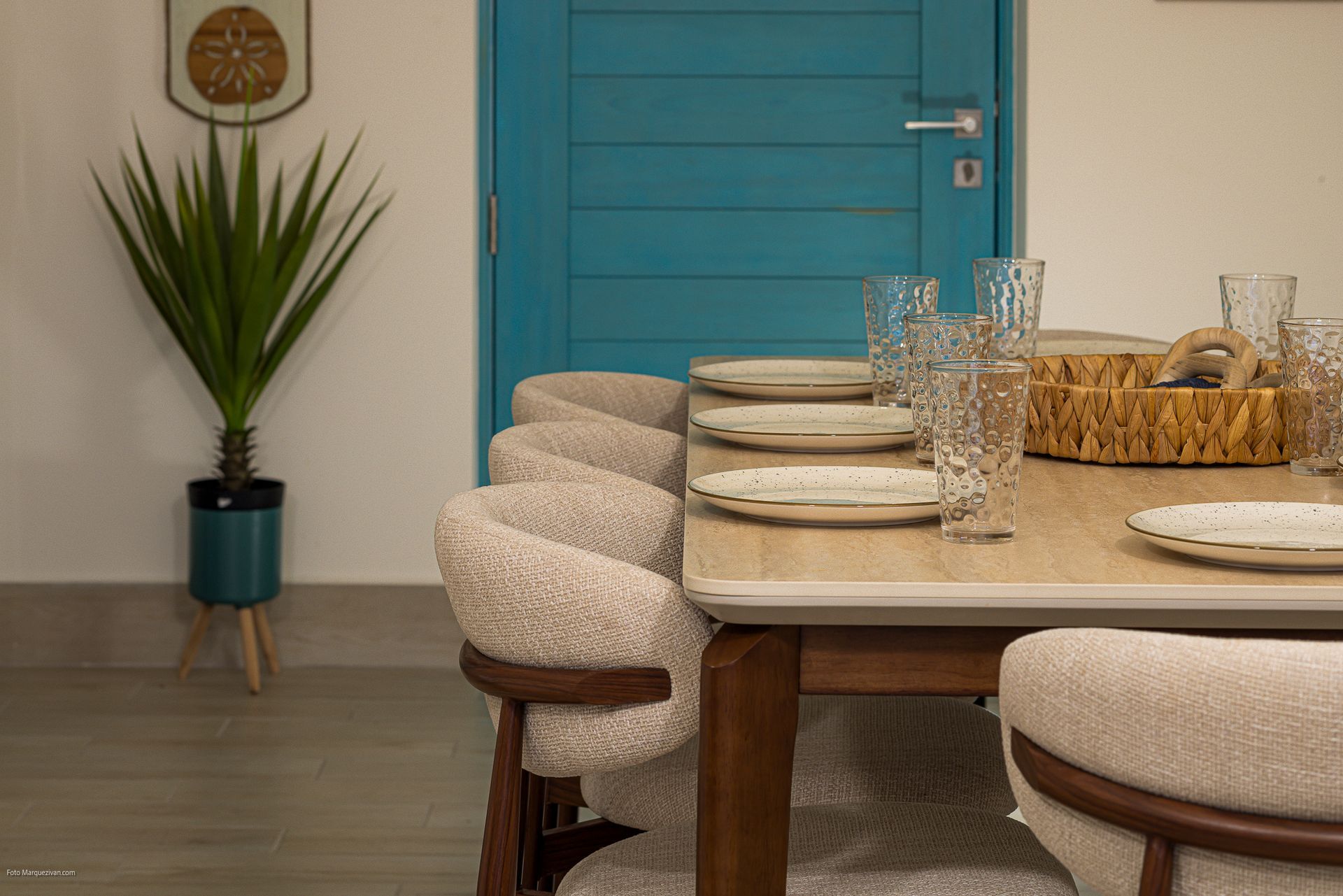 Dining area detail of a Playa Caracol apartment with boucle chairs and turquoise accent door, interior design by Furnishing Solutions Panama.