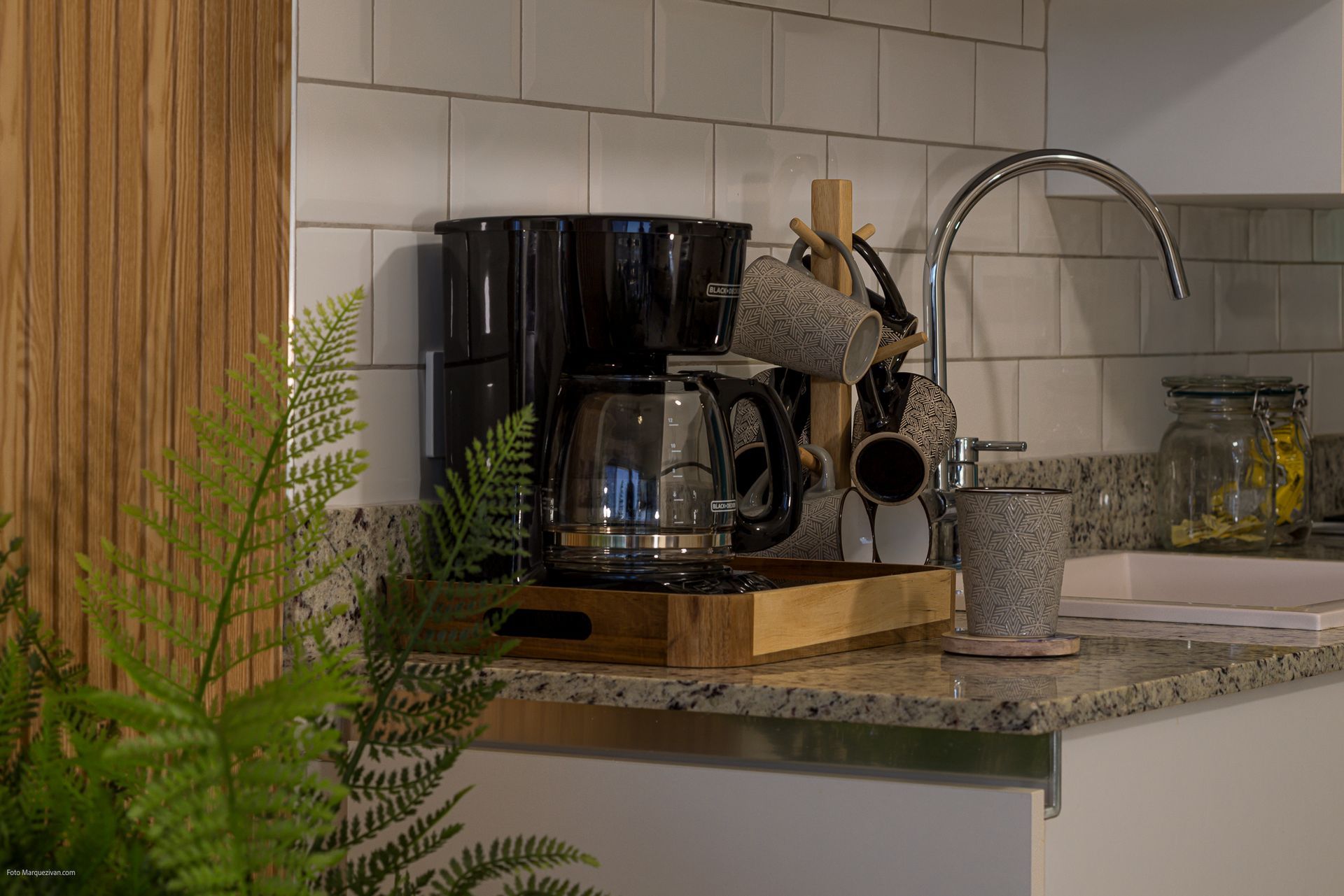 Kitchen detail of a Playa Caracol apartment with coffee station, curved faucet and natural wood paneling, interior design by Furnishing Solutions Panama.