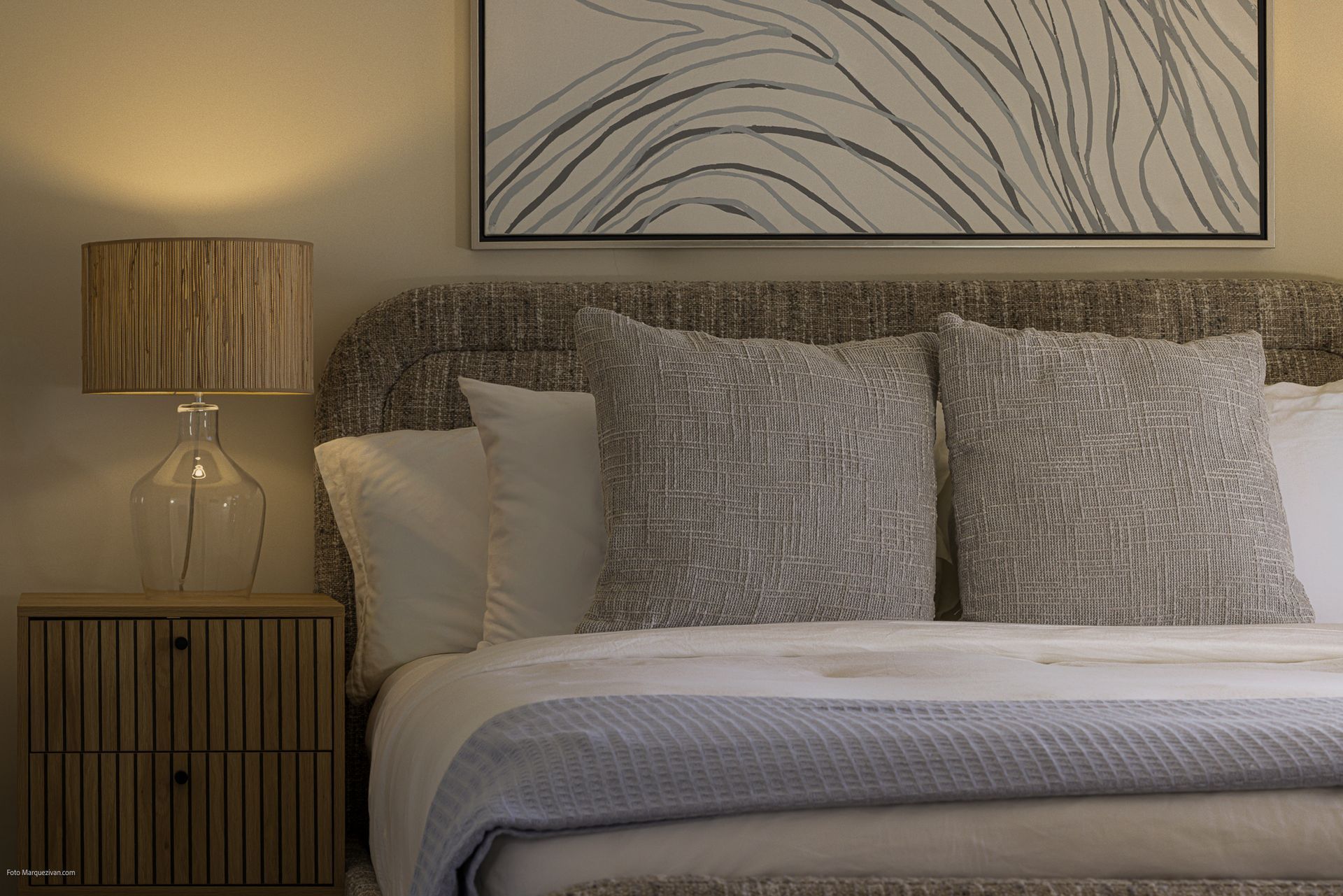 Bedroom detail of a Playa Caracol apartment with textured cushions, upholstered headboard and rattan lamp, interior design by Furnishing Solutions Panama.
