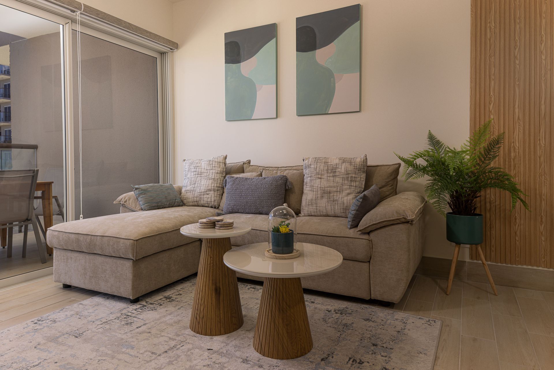 Living area of a Playa Caracol apartment with beige sectional sofa, abstract art and wood coffee tables, interior design by Furnishing Solutions Panama.