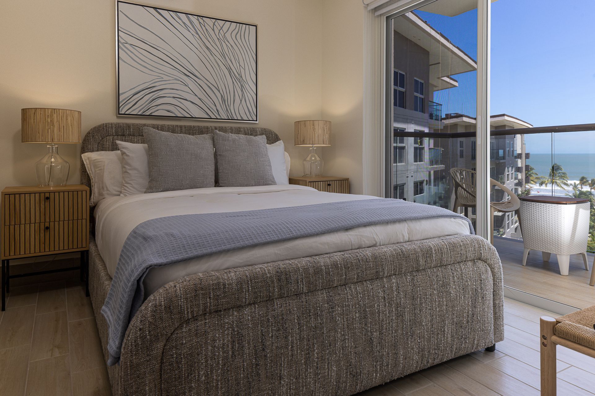 Master bedroom of a Playa Caracol apartment with upholstered bed and Pacific Ocean balcony view, interior design by Furnishing Solutions Panama.