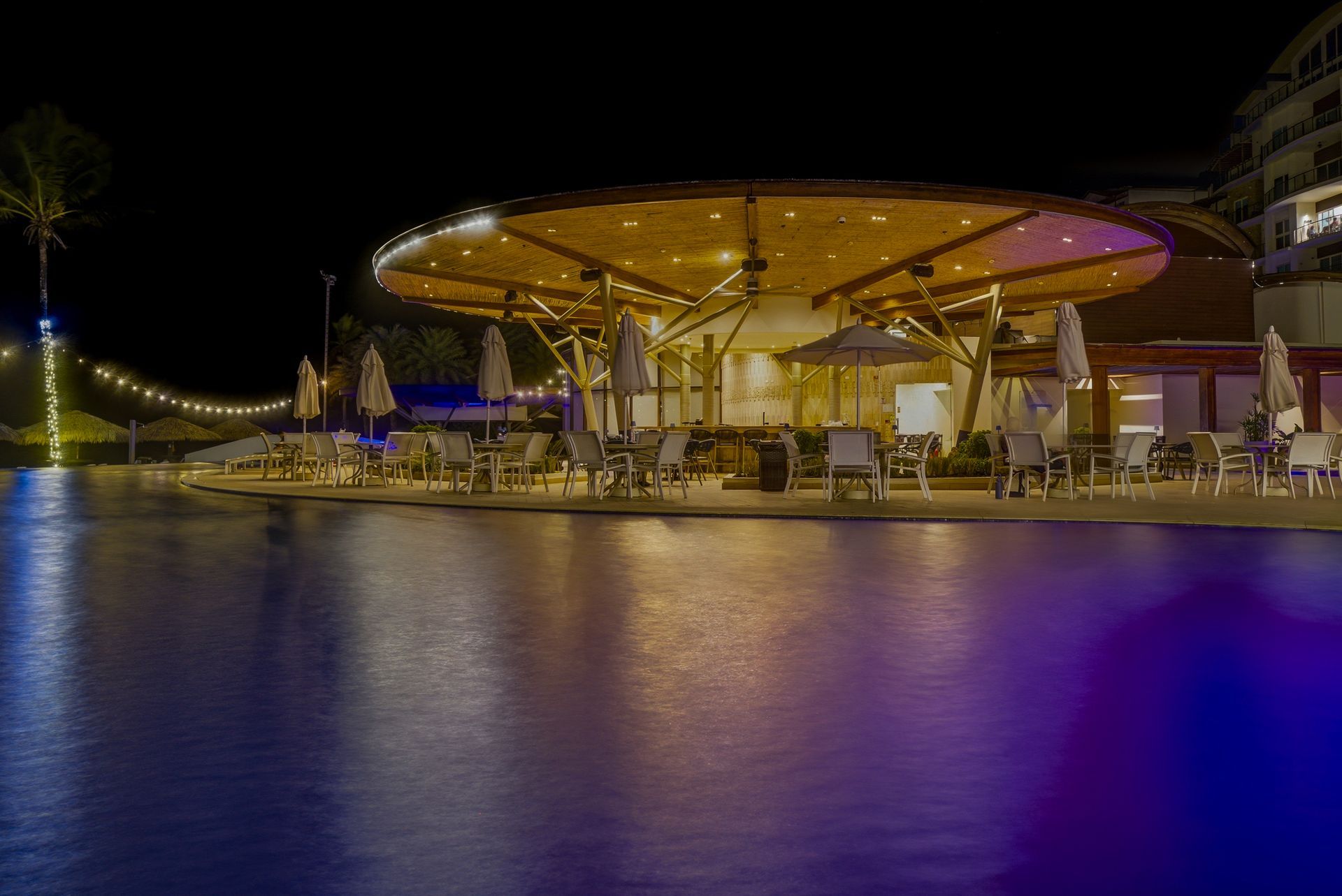 Night photography of illuminated beach clubhouse reflected on pool at Playa Escondida Resort