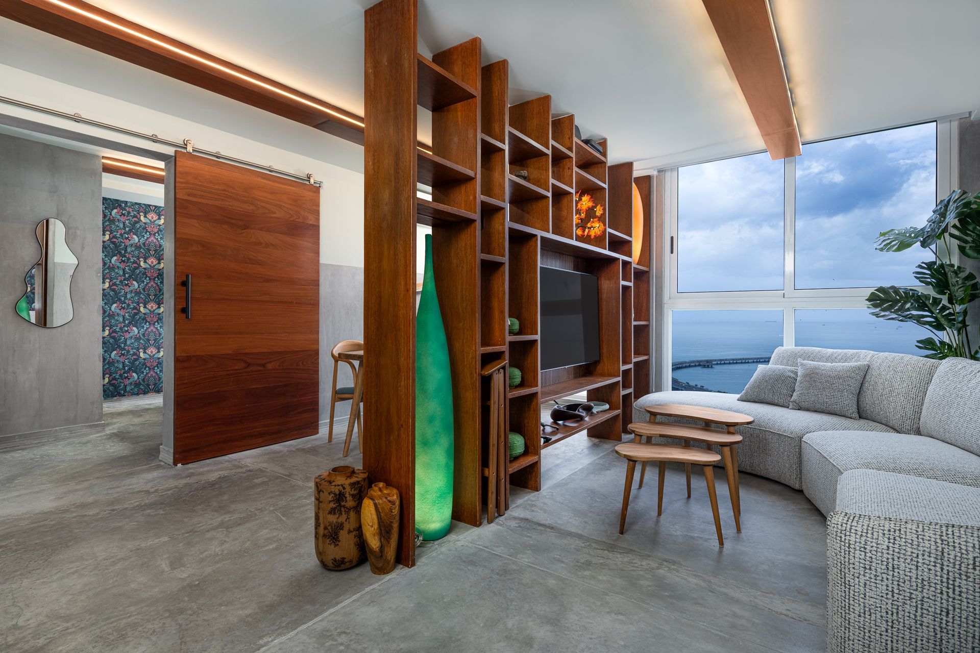 Living room with wooden shelves, sofa, and sliding door. Features a view of the water.real estate photos by ivan marquez panama