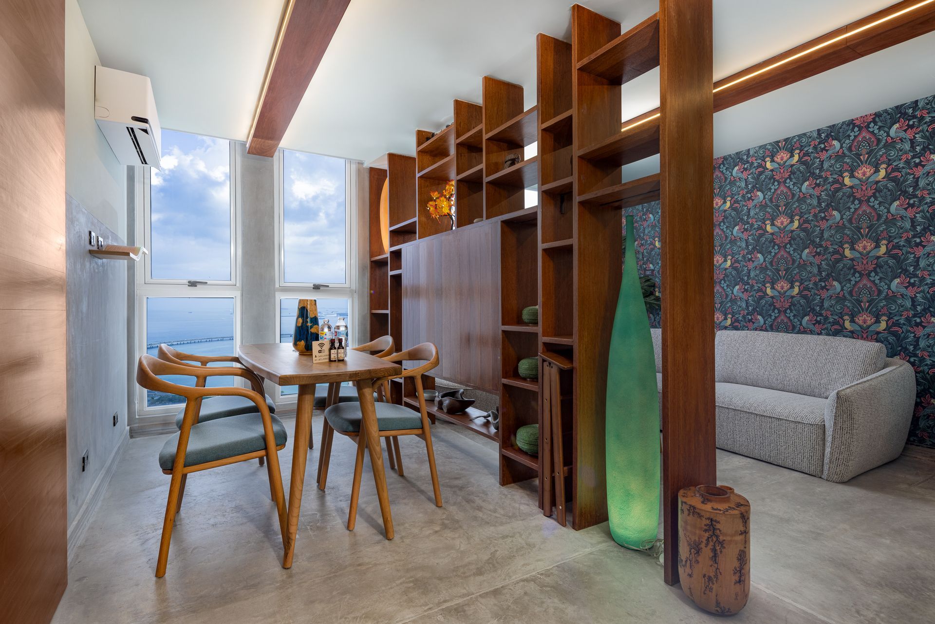 Dining area with wooden furniture, open shelving, and a sofa with floral wallpaper. Bright natural light.real estate photos by ivan marquez panama