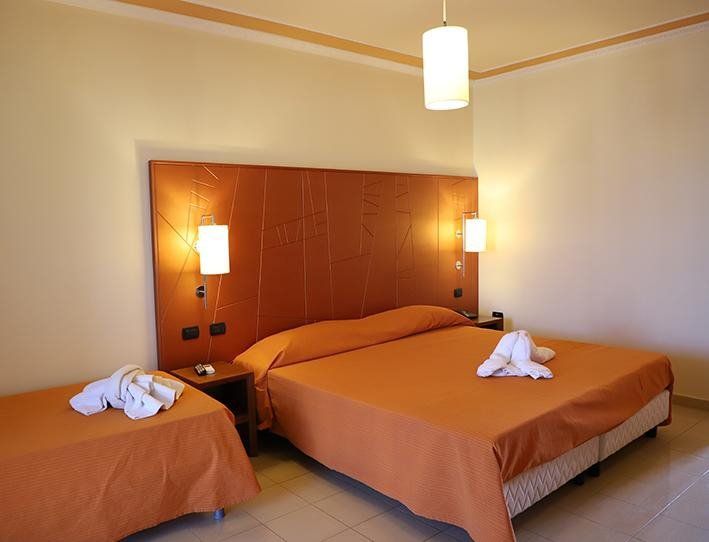 Una camera d'albergo con un letto king size e due letti singoli
