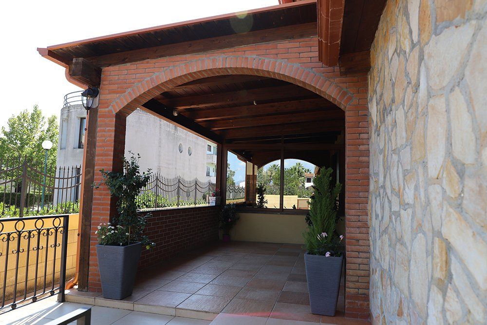 Un edificio in mattoni con un arco in legno e piante in vaso