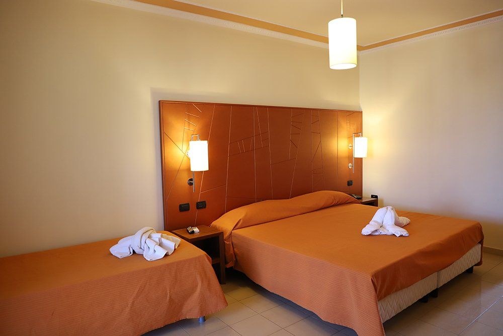 Una camera d'albergo con un letto grande e due letti più piccoli