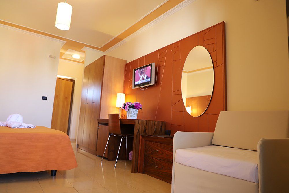 Una stanza d'albergo con un letto, una sedia, una scrivania e una televisione.