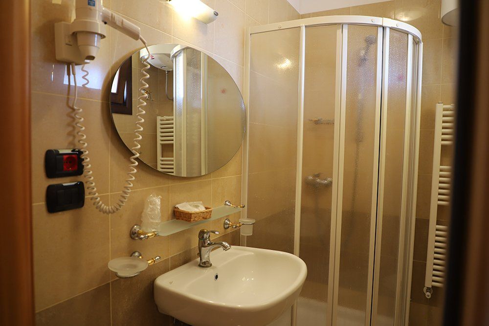 Un bagno con lavandino, doccia, specchio e asciugacapelli.