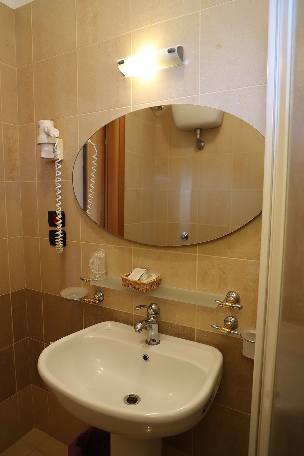 Un bagno con lavandino, specchio e asciugacapelli.