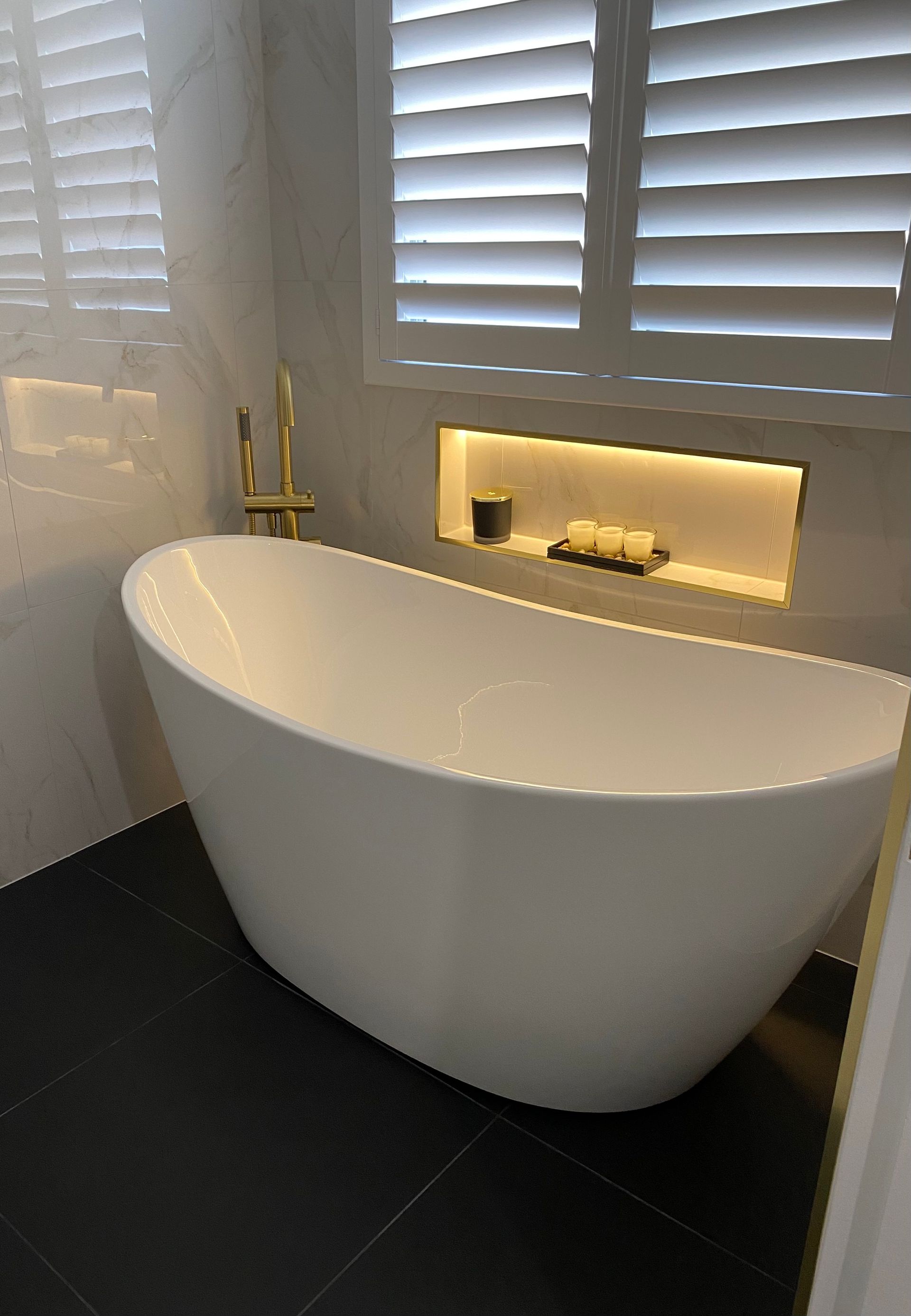 A White Bathtub Is Sitting In A Bathroom Next To A Window — Coffs Coast Designer Bathrooms in Toormina, NSW
