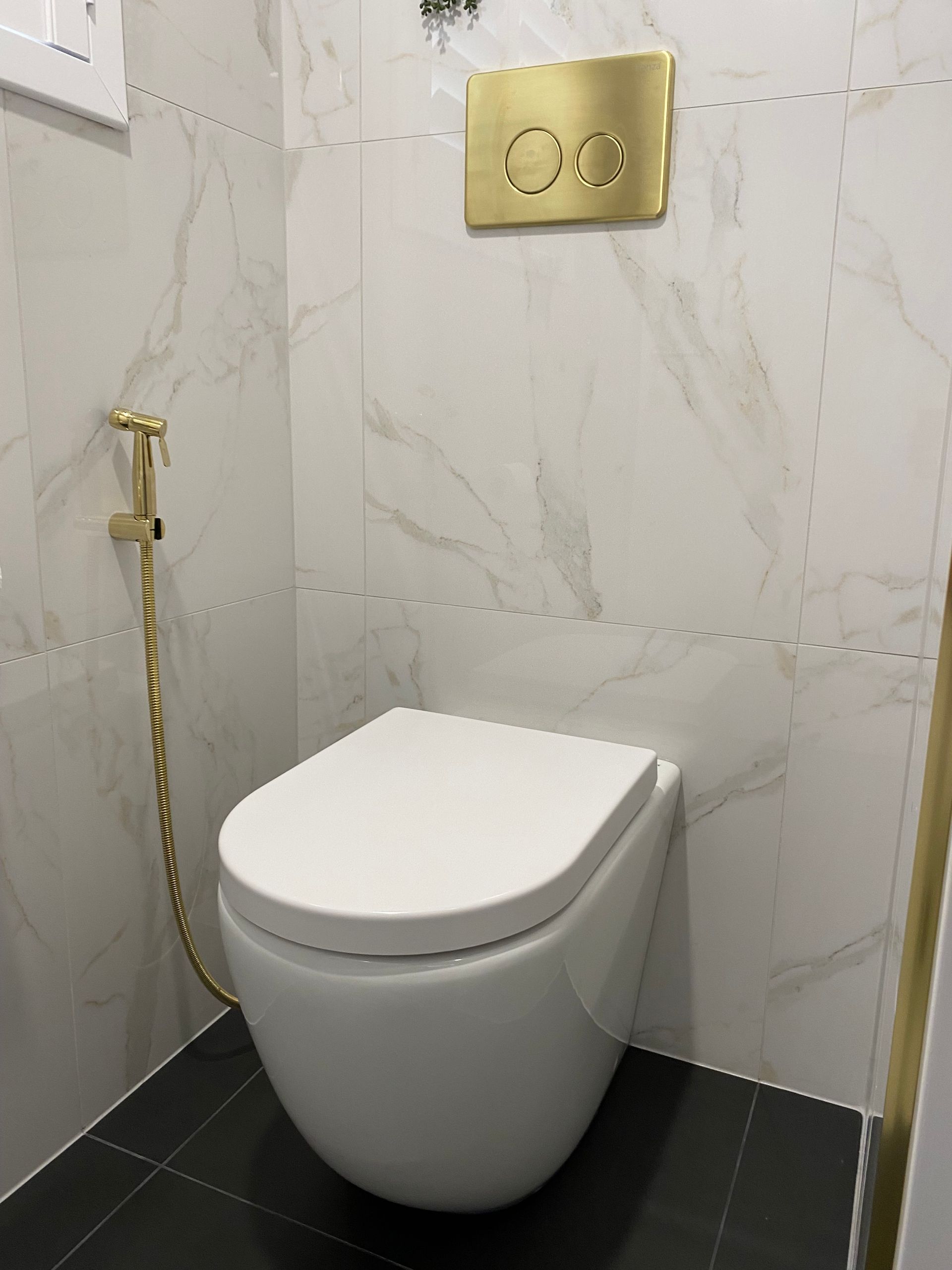 A Toilet With A Hose Attached To It In A Bathroom — Coffs Coast Designer Bathrooms in Toormina, NSW