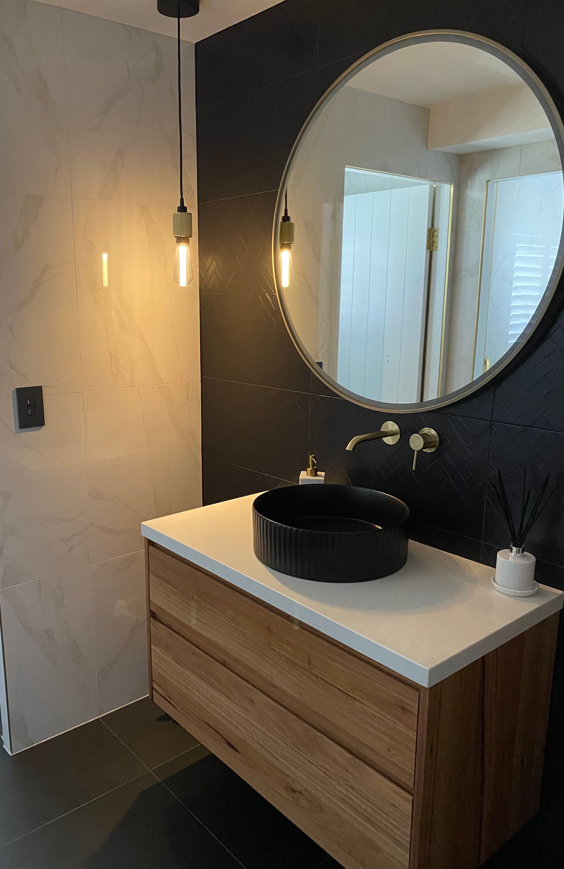 A Bathroom With A Black Sink And A Round Mirror — Coffs Coast Designer Bathrooms in Toormina, NSW