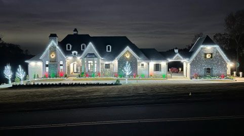 A large house is decorated with christmas lights at night.