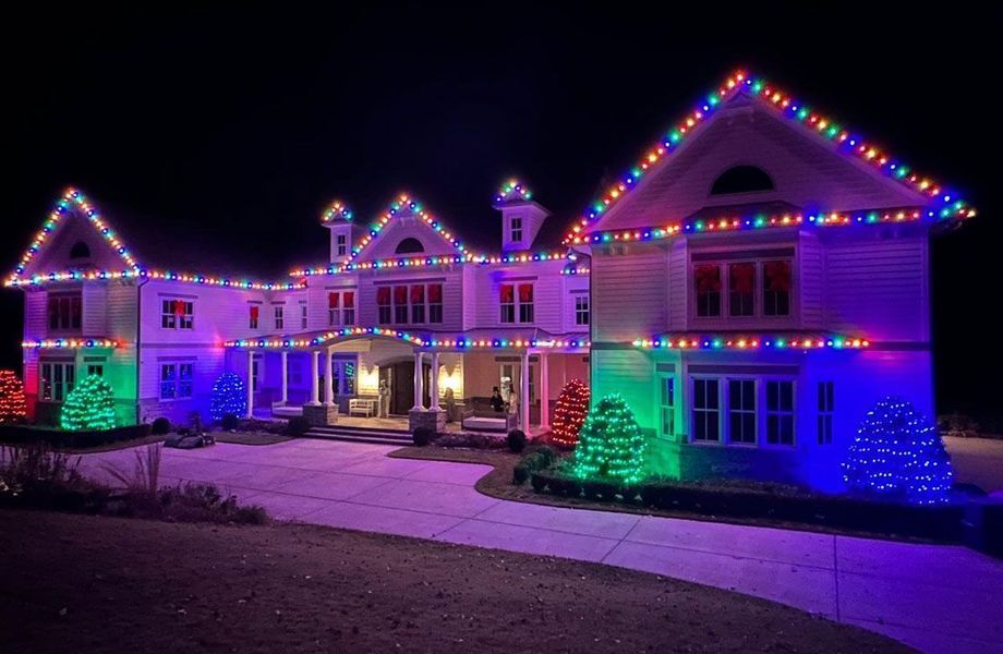 A large house is decorated with christmas lights at night.