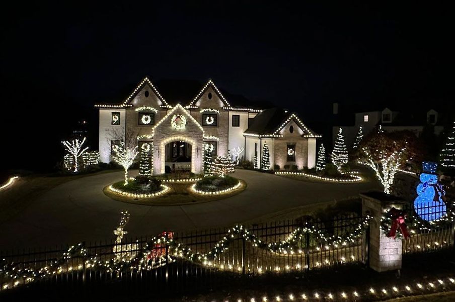 A large house is decorated with christmas lights at night.