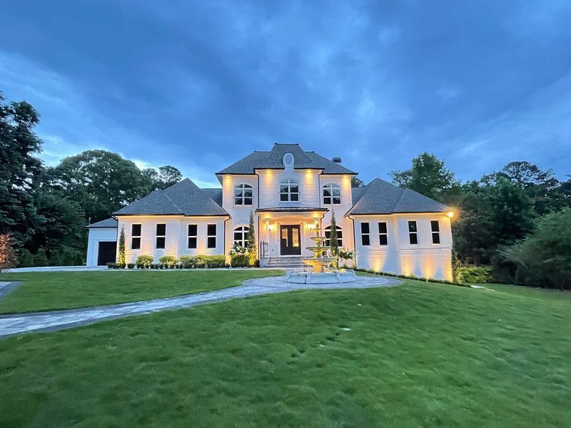 A large white house with a lot of windows is lit up at night.