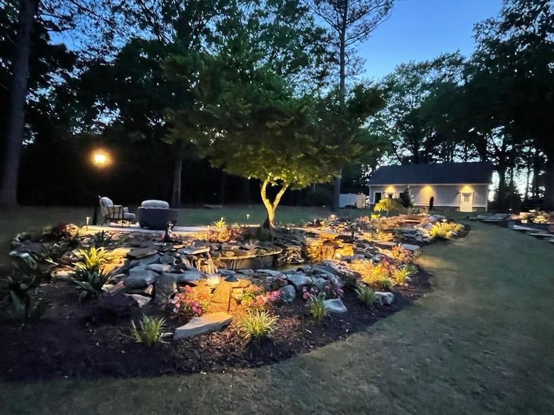 A house is behind a lush green garden at night