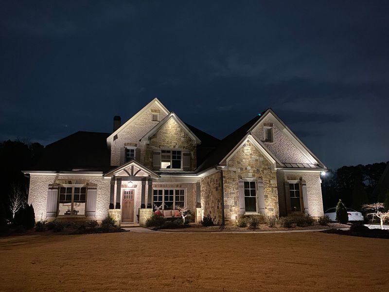 A large house is lit up at night with a dark sky in the background