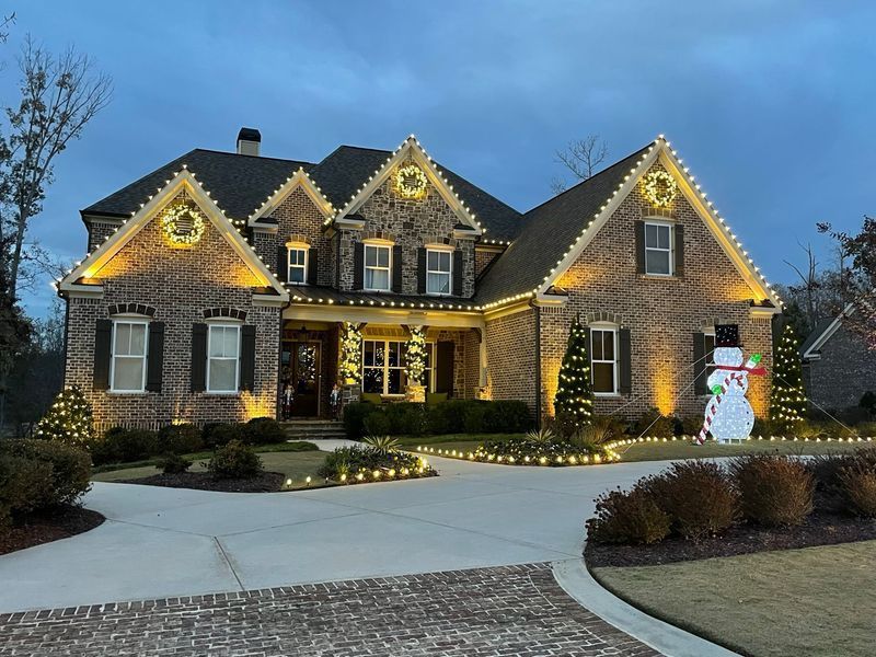 A large brick house decorated with christmas lights and a snowman