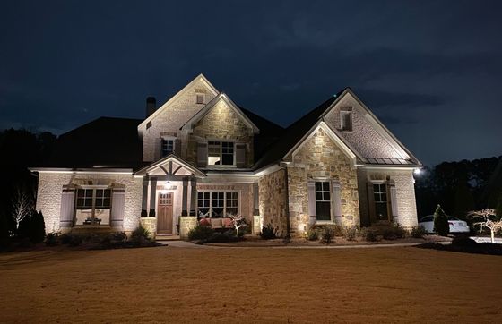 A large stone house is lit up at night.