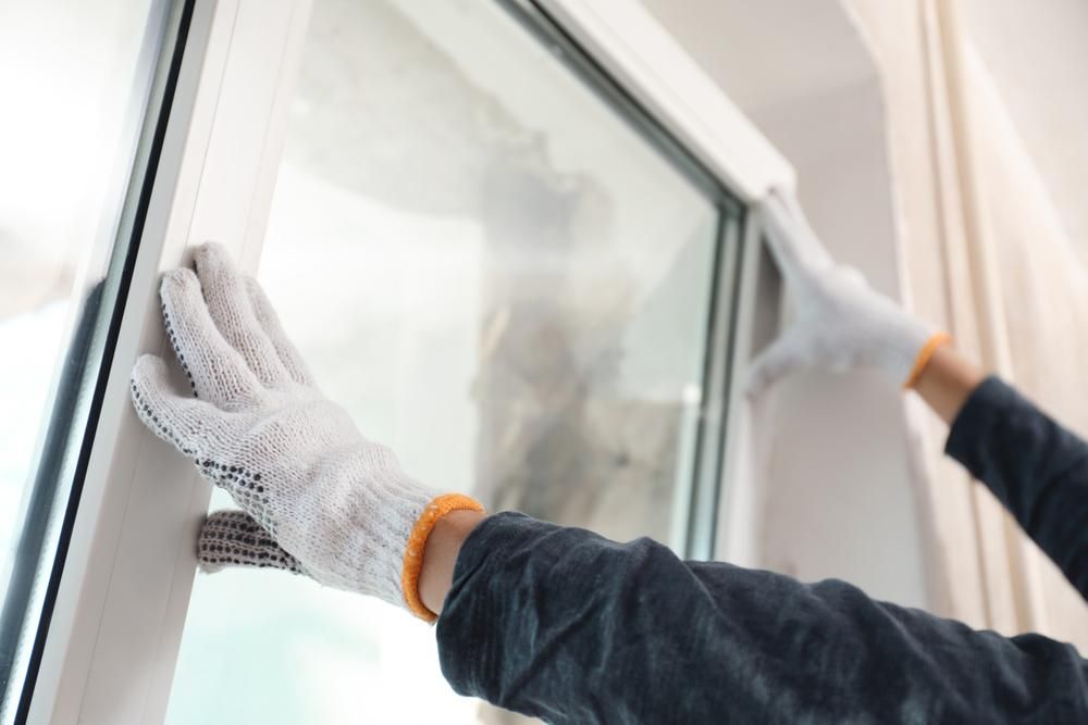 A Person Wearing Gloves Is Cleaning a Window — Highline Carpentry in Kahibah, NSW
