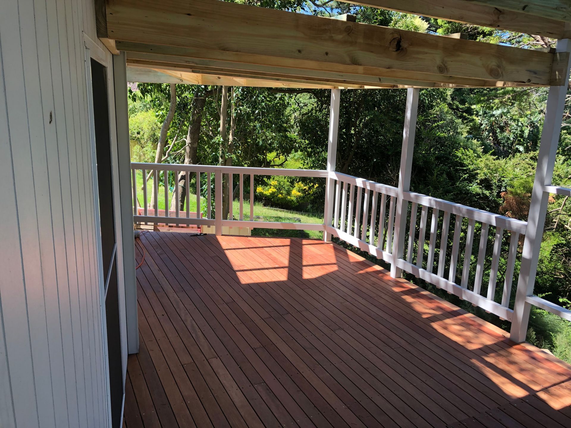 A Gray Deck with A White Railing Is in Front of A Blue House — Highline Carpentry in Kahibah, NSW
