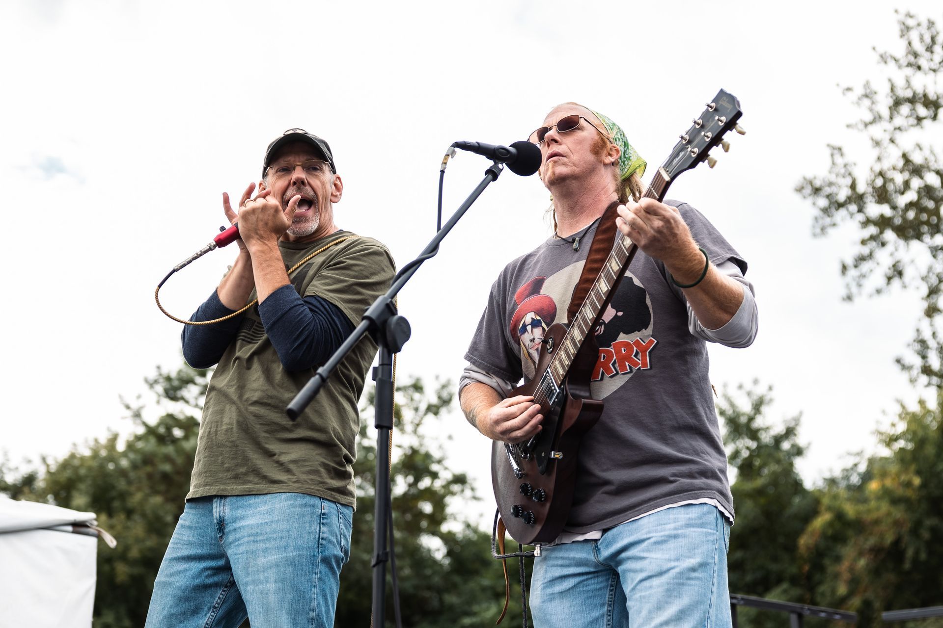 Two men are playing guitars and singing into microphones on a stage.