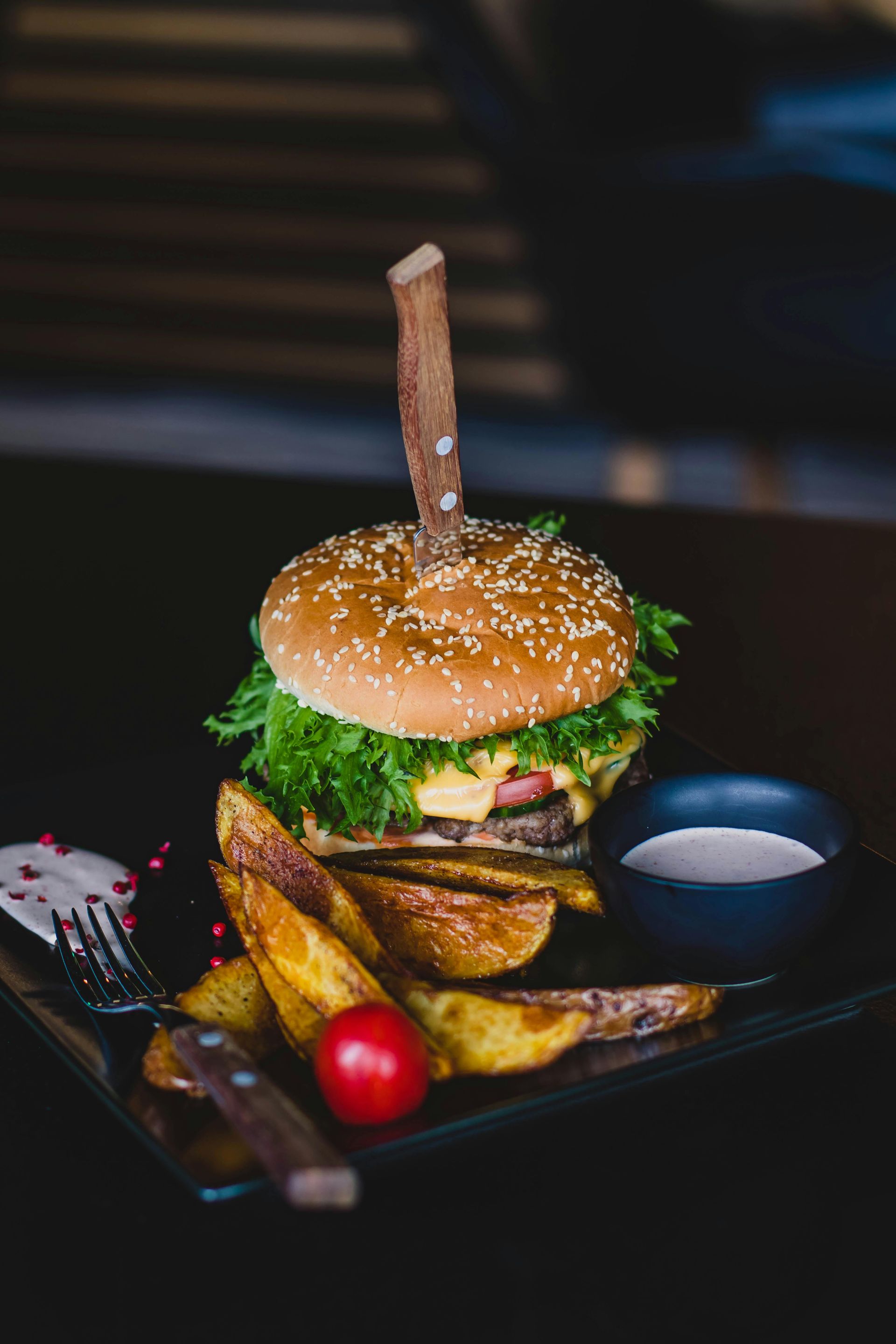 A hamburger and french fries on a black plate on a table.