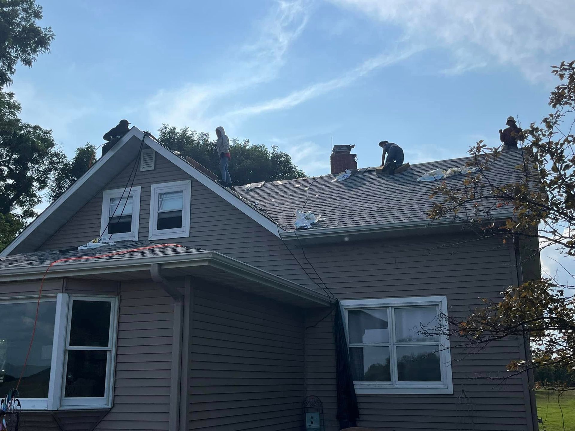 A group of people are working on the roof of a house.