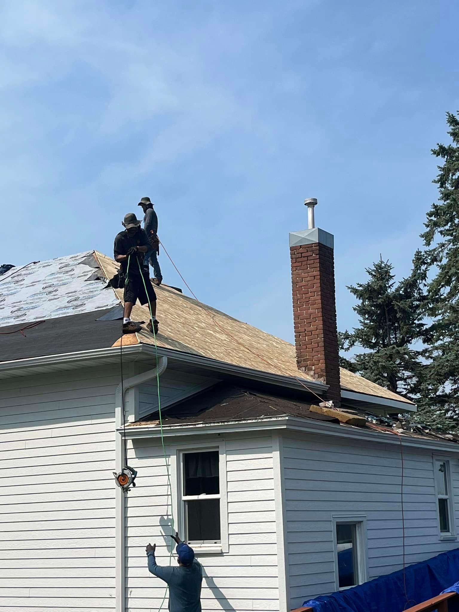 Two men are working on the roof of a house.