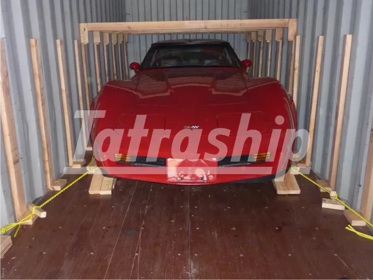A red car is sitting inside of a container that says tatraship