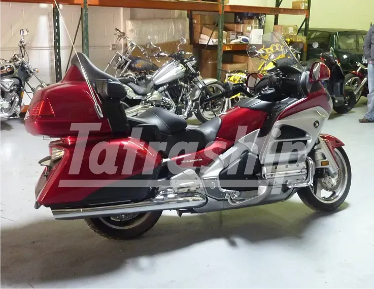 A red motorcycle is parked in a warehouse with the word tatra on the side