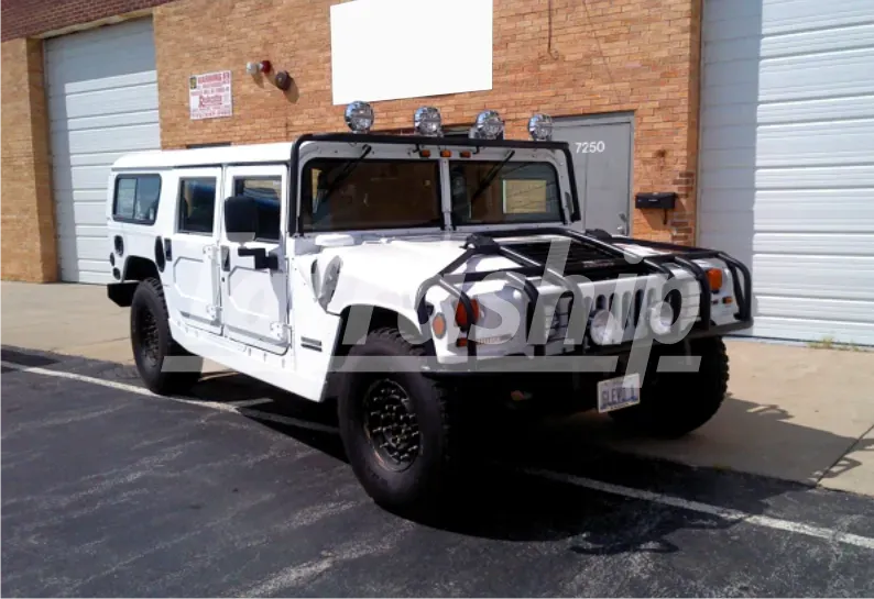 A white hummer is parked in front of a brick building