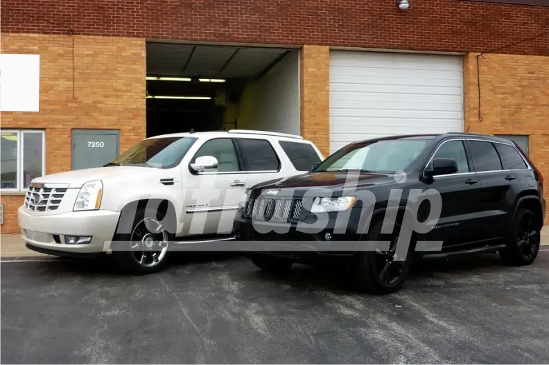 A white suv and a black suv are parked in front of a brick building