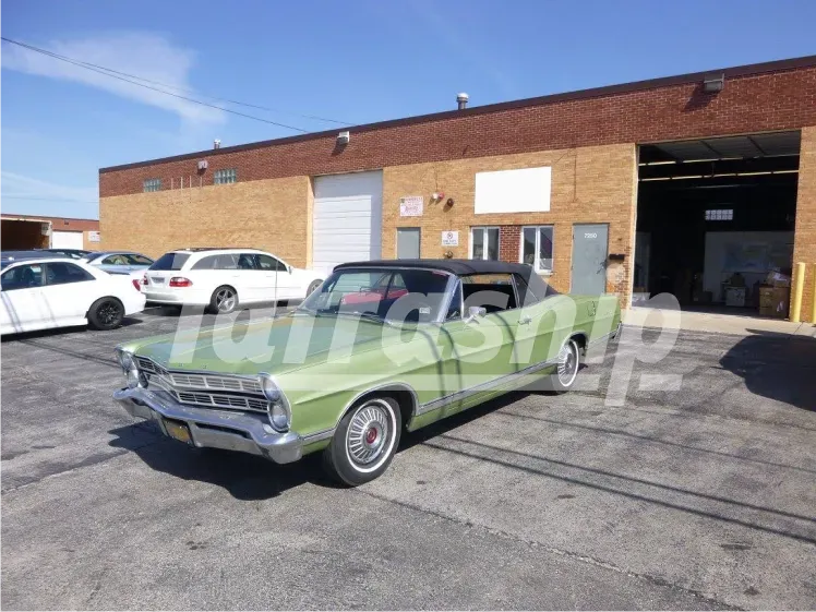 A green car is parked in front of a brick building