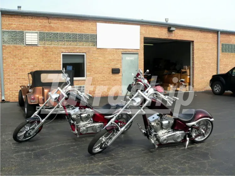 Two chopper motorcycles are parked in front of a brick building
