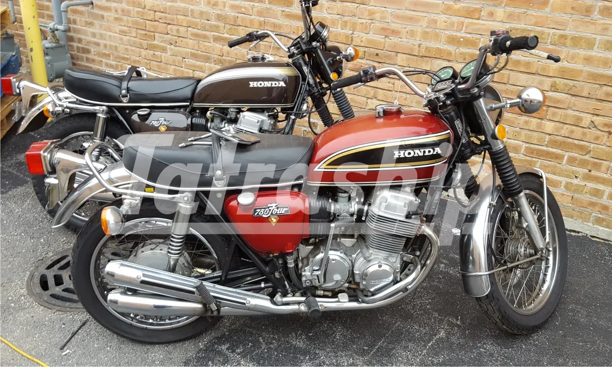 Two honda motorcycles are parked next to each other in front of a brick wall.