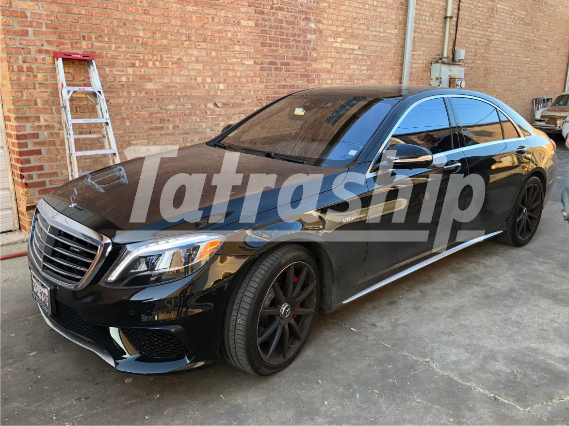A black mercedes benz is parked in front of a brick building.