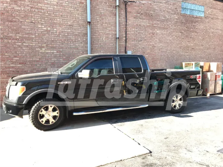 A black pickup truck is parked in front of a brick building.