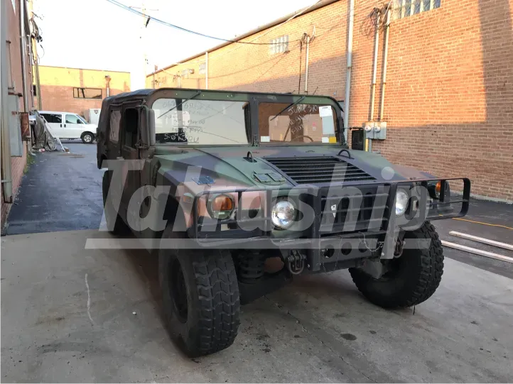 A military vehicle is parked in front of a brick building.