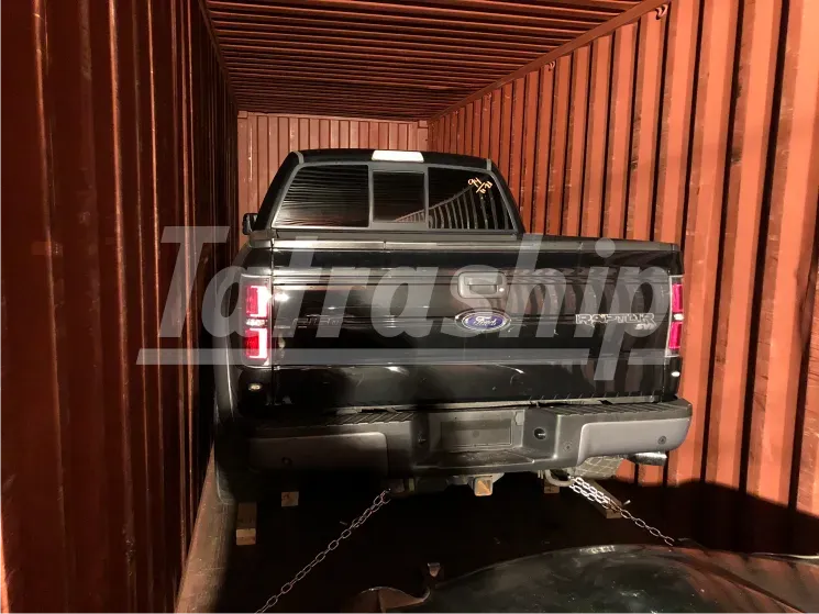 A black ford truck is in a shipping container
